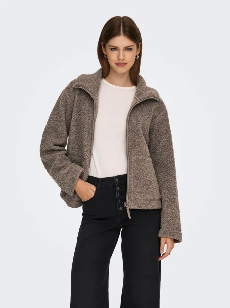 Herbstlook für Damen mit taupefarbener Teddyjacke und schwarzer Jeans